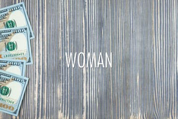 WOMAN - word (text) on wooden background, money, dollars. Business concept (copy space).