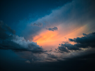 Naklejka na ściany i meble Orange light among the dark storm cloudscape