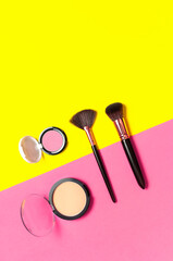Obraz na płótnie Canvas Cosmetic makeup Set. Professional makeup brushes, powder, eyeshadow, blush, lipstick on yellow pink background flat lay top view copy space. Beauty product women's accessory fashion. Different brushes