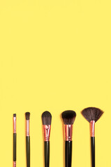 Beauty product, makeup, women's accessory, fashion. Professional makeup brushes on Illuminating yellow background flat lay top view copy space. Different brushes. Cosmetic makeup Set