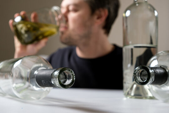 A man with alcohol dependence drinks brine from a jar of aole cucumbers, a man in a hangover.