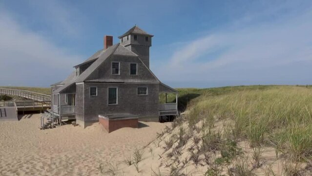 Blue sky and dunes with grass in front of the life saving station building in Provincetown	