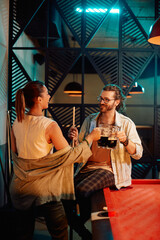 Happy couple toasts with beer while playing snooker in pool hall.