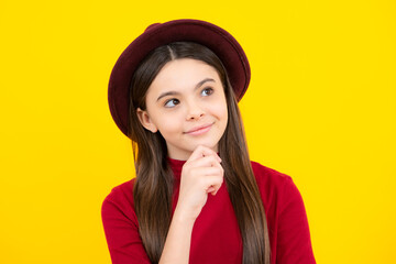 Happy teenager portrait. Thoughtful teenager girl touch chin and thinking, pensive child making idea, posing isolated on yellow studio background. Smiling girl.