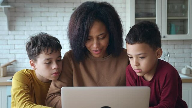 Close-up mixed race family portrait of a single African American mother and two kids sons making choices about online shopping,purchases, booking, ticketing , enjoying day off, surfing on web sites