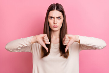 Portrait of attractive grumpy brown haired girl showing thumb down no against isolated over pink...