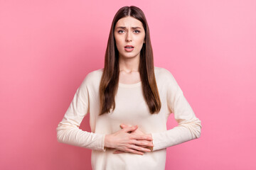 Obraz premium Portrait of attractive sick girl touching belly feeling bad isolated over pink pastel color background