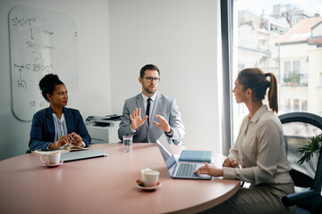 Male CEO communicating with colleagues during business meeting in office.