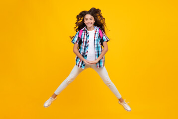 Fototapeta na wymiar School girl in school uniform with school bag. Schoolchild teenager hold backpack on yellow isolated background. Crazy run and jump.