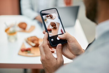 Close up of businessman photographing his breakfast with smart phone in cafe.