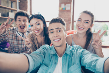 Photo of charming cute groupmates sitting dormitory beanbags showing v-signs tacking selfie indoors workstation workshop