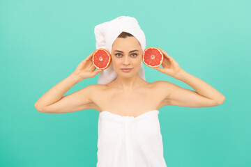 cheerful young woman in towel with healthy skin hold grapefruit on blue background