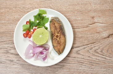 salty dry Indo-Pacific king mackerel fish topping chop shallot and chili with slice lemon salad on plate