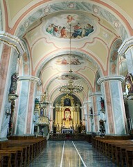 Fototapeta na wymiar church interior, church pews, large altar in church, paintings on ceiling, golden altar, chandelier hanging from a long pole, decorations, ornaments, marble floor