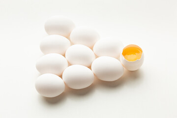 White eggs on a white background, one egg is broken, unlike the others.