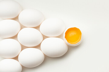 White eggs on a white background, one egg is broken, unlike the others.