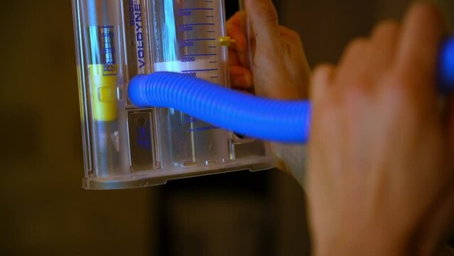Side view of a man using a spirometer.