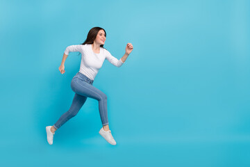 Fototapeta na wymiar Photo of charming pretty lady dressed white shirt jumping high running empty space isolated blue color background