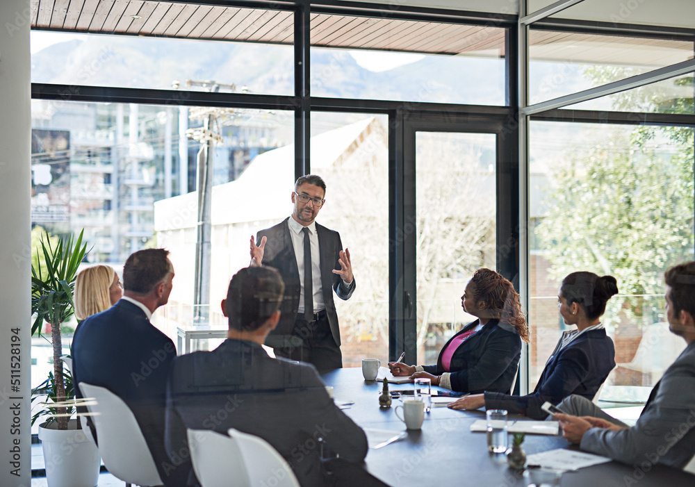 Poster Running them through the plan. Shot of an executive giving a presentation to colleagues in a boardroom.