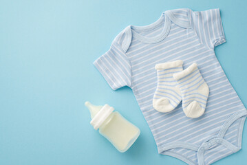 Baby accessories concept. Top view photo of blue infant clothes bodysuit socks and milk bottle on...