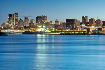 Obraz premium Skyline of Montreal illuminated at dusk over the St Lawrence river illuminated at dusk