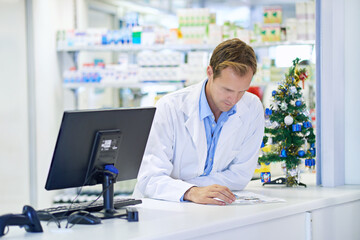Planning his christmas specials. A pharmacist reading something on his counter.
