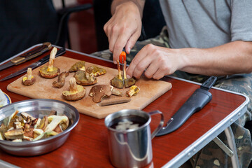 Hands cut raw mushrooms with sharp knife.