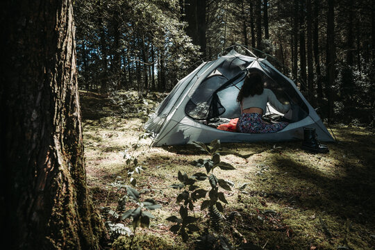 Woman inside a camping tent in the woods