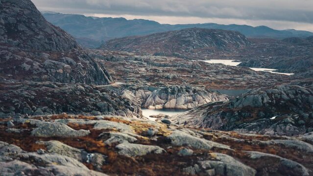 Barren and outlandish landscape. Rocky terrain stretches up to the horizon. Stone cairns are scattered through the landscape. Slow-motion, pan right shot.