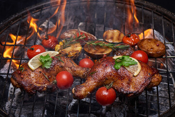 Grilled chicken legs on the flaming grill with grilled vegetables with tomatoes, potatoes, pepper seeds, salt. top view with copy space. tasty snack. flat lay. healthy lunch menu. diet food.