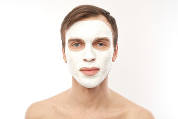 Portrait of young handsome man with cosmetic mask on his face isolated on white background