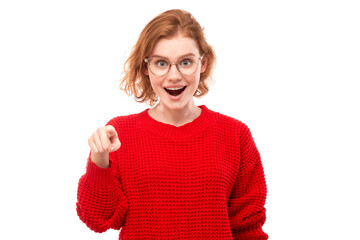 Portrait of friendly redhead girl chooses you, points finger at the camera isolated on white background