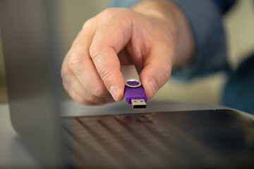 male hand connects usb flash drive in a laptop device
