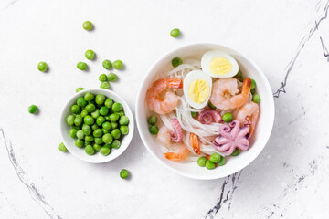 Fototapeta na wymiar A traditional dish of Asian cuisine. Rice vermicelli with shrimps, bebe octopus and green peas
