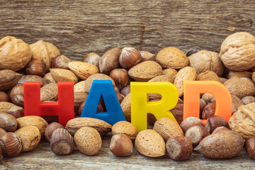 The word HARD is lined with color letters in a pile of assorted nuts