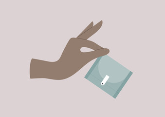 A hand holding a plastic sanitary pad packet, menstruation accessories © nadia_snopek