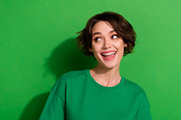 Photo of satisfied young person toothy smile look interested empty space isolated on green color...