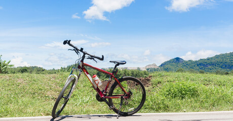 Fototapeta na wymiar red mountain bike on country road and the clouds in the blue sky