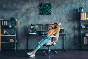 Full length body size view of attractive dreamy girl web developer expert sitting in chair resting at workplace workstation indoors - obrazy, fototapety, plakaty