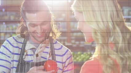 Animation of financial graphs over happy caucasian male seller and female customer in grocery shop - Powered by Adobe