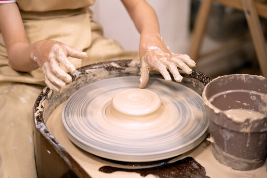 Human hands and potter's wheel. Hands of a child making a cup on a potter's wheel.