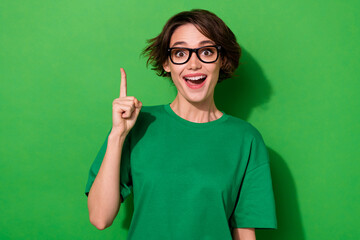 Photo of pretty excited young lady dressed casual t-shirt eyewear pointing empty space isolated...