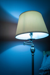 The rustic lamp stand light illuminating the blue-colored wall in the room 