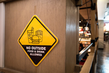 No outside food and drink allowed text on black and yellow restriction sign in restaurant