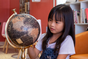 Girl spinning a mock globe for fun.