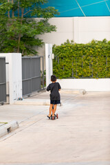 Children playing scooter on the roadside near the house