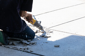 Builder worker with pneumatic hammer drill equipment breaking concrete at floor