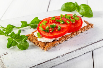 Crispbread with curd cheese, tomatoes, green onions, arugula and basilica. Delicious and healthy breakfast