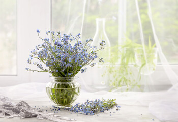 Bouquet of forget-me-nots in a vase on a white windowsill