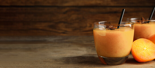 Tasty persimmon smoothie with anise and straw on wooden table, space for text. Banner design